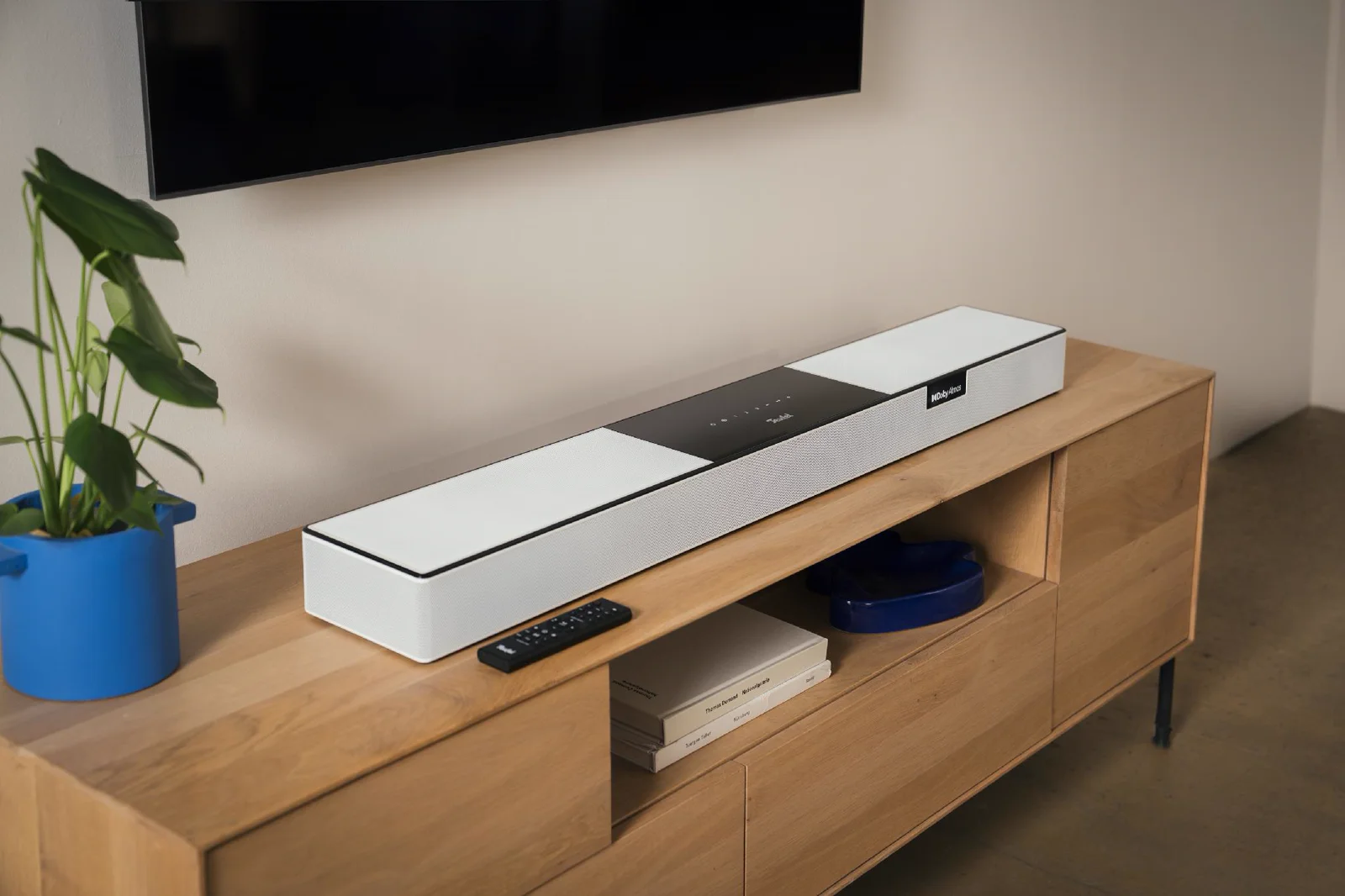 Teufel CINEBAR PRO 2 en blanco sobre un mueble de televisión, con los altavoces que disparan hacia el techo en la parte superior